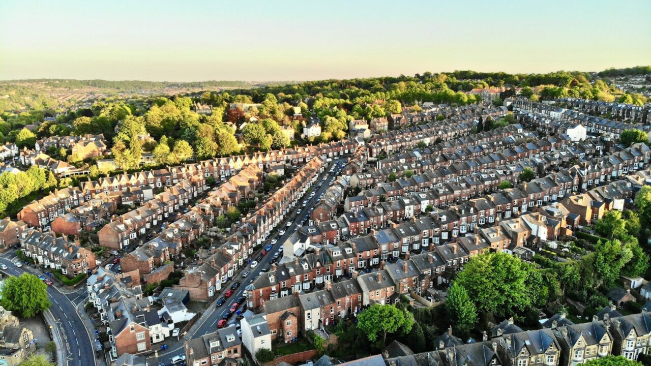 Aerial view of a suburban residential area with rows of terraced houses and green spaces