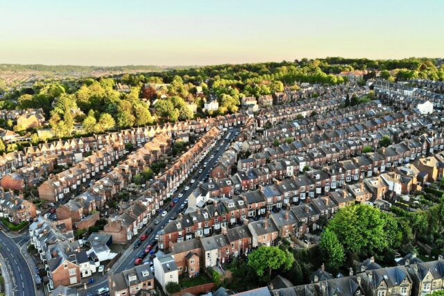 Aerial view of a suburban residential area with rows of terraced houses and green spaces