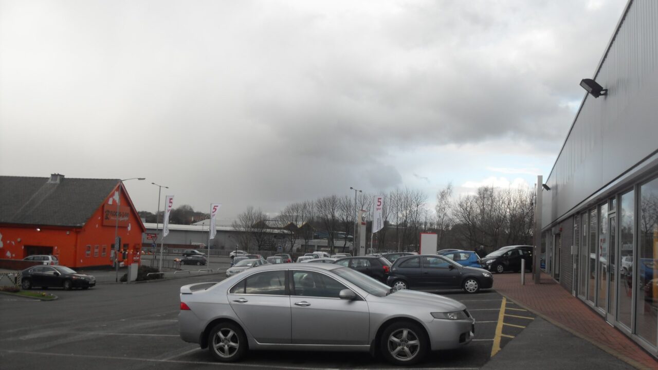 A forecourt of a car dealership in Bury showing parked vehicles outside the showroom