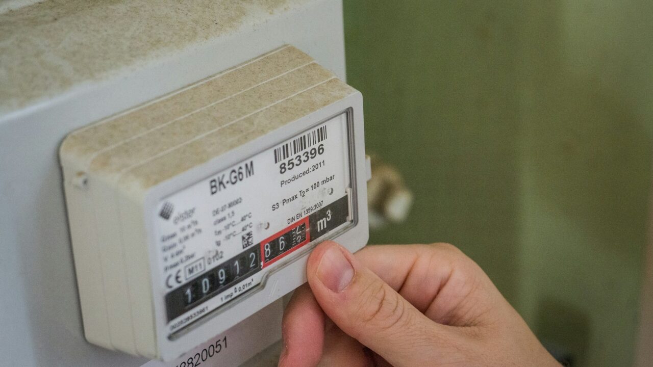 A hand holding a white smart meter with a black and red label