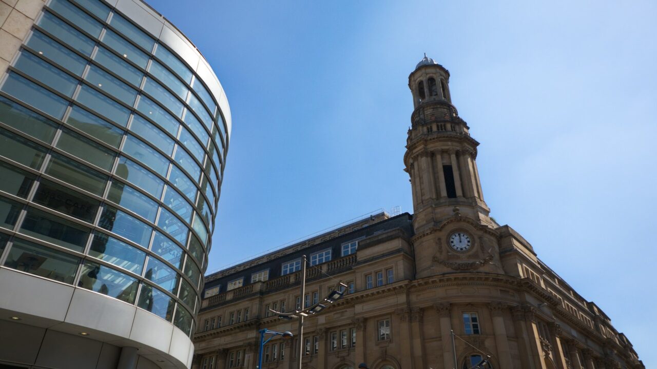 A large building with a clock tower and classical architecture against a blue sky