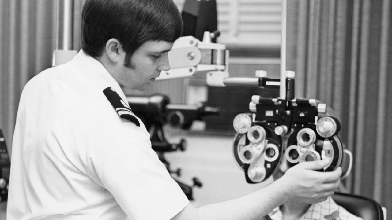 Optometrist examining a patient's eyes using a phoropter during an eye test