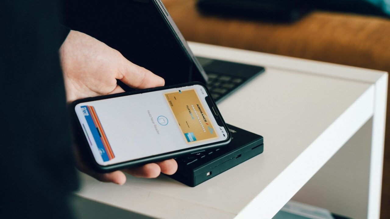 Person holding a smartphone over a card reader for contactless payment