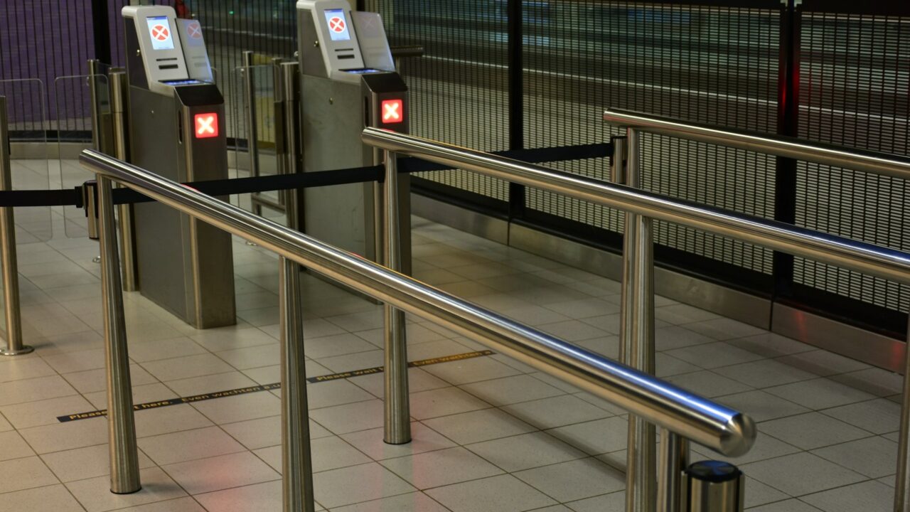 Metal turnstiles and railings at a transit station entrance