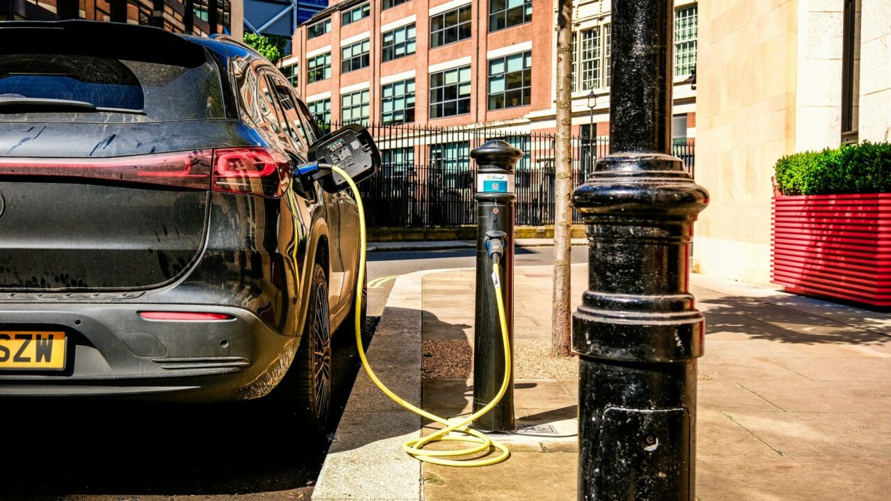 Electric car plugged into a street-level charging station on a UK urban pavement