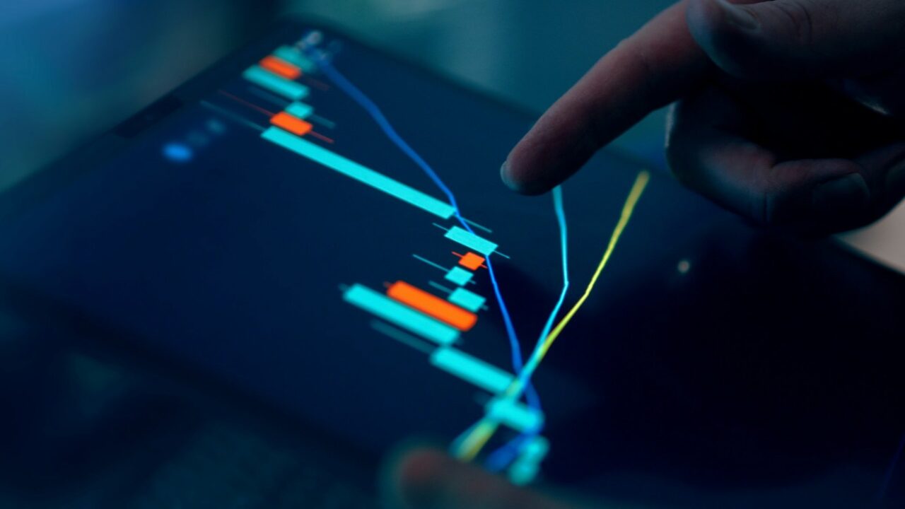 Fingers interacting with a stock market graph displayed on a tablet screen