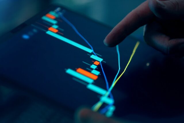 Fingers interacting with a stock market graph displayed on a tablet screen