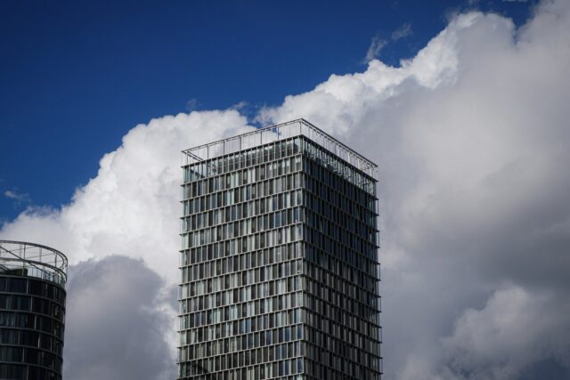 A tall modern office building against a blue sky with white clouds