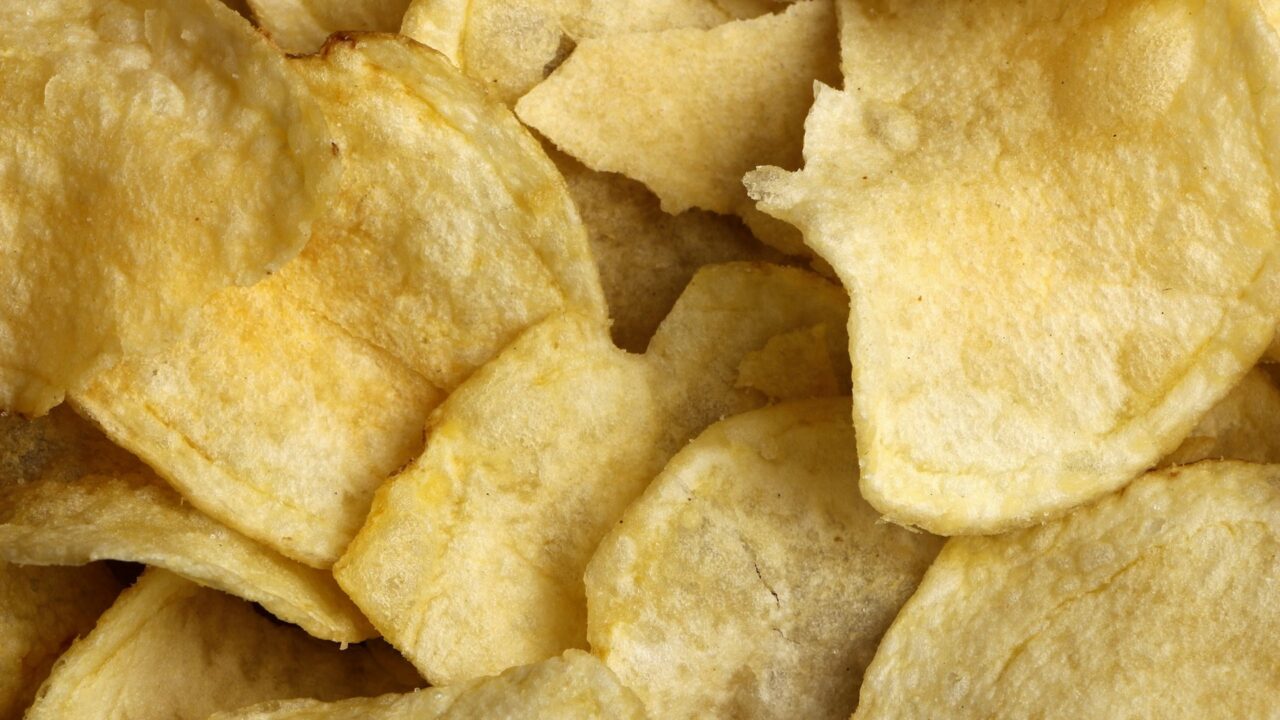 Golden-brown potato crisps scattered on a neutral surface