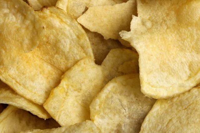 Golden-brown potato crisps scattered on a neutral surface