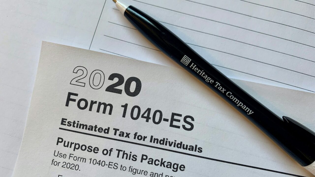 A black pen resting on a 2020 Form 1040-ES tax form with lined paper in background