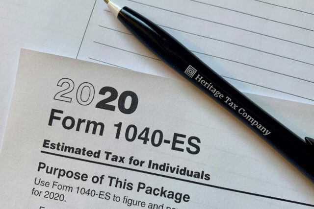 A black pen resting on a 2020 Form 1040-ES tax form with lined paper in background