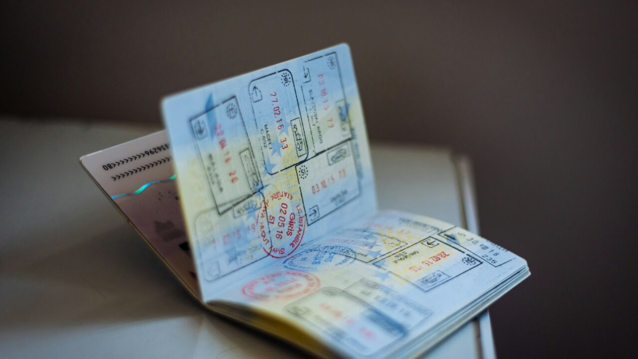 An open passport displaying multiple ink stamps on its pages, lying on a table