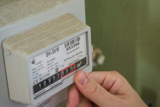 Close-up of a hand holding a white smart meter device with black and red label