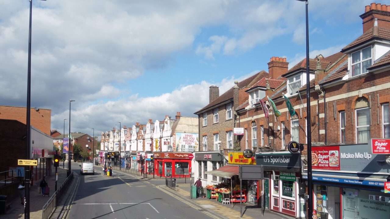 A row of shops on a British high street with various storefronts visible