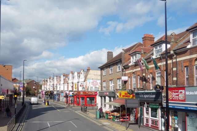 A row of shops on a British high street with various storefronts visible