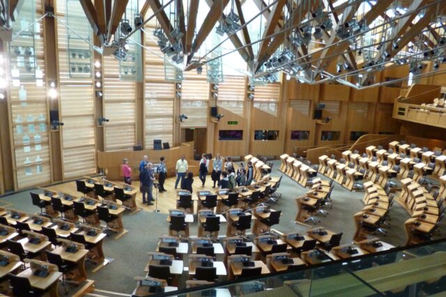 Interior of the Scottish Parliament debating chamber at Holyrood with tiered seating and parliament in session