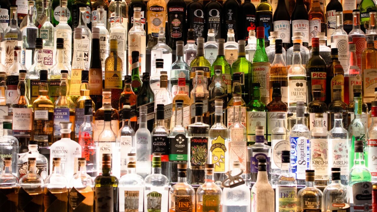 Multiple bottles of assorted spirits, wines, and liqueurs displayed together on shelves