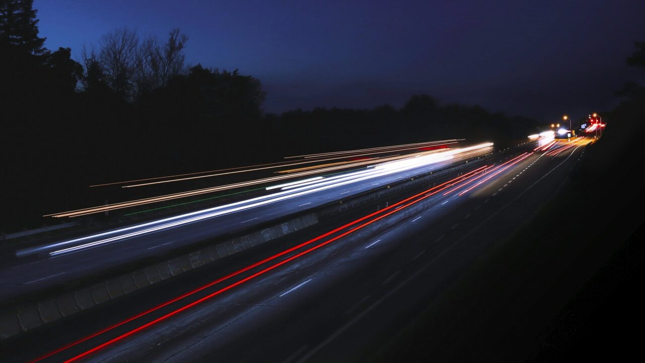 Long exposure photograph of a nighttime highway showing red and white light trails from vehicle headlights and taillights.