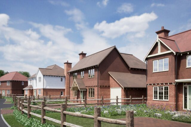 A row of red brick houses with white trim next to a residential road with fencing