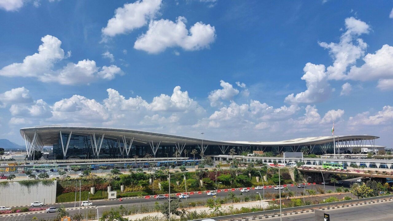 Modern airport terminal building with curved architecture against blue sky with white clouds