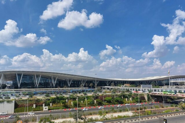 Modern airport terminal building with curved architecture against blue sky with white clouds