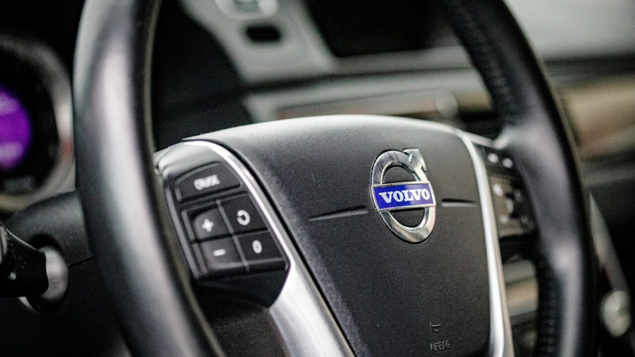 Close-up of a car steering wheel with a blue Volvo logo badge in the center