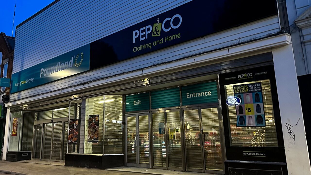 Poundland store with closed metal shutters on a High Street in Gillingham, Kent, at dawn